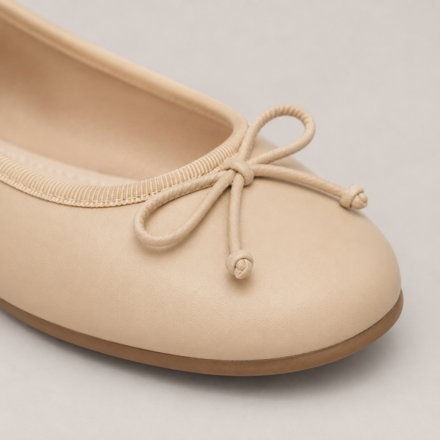 Gros plan sur le nœud discret d’une ballerine beige à bout rond pour femme