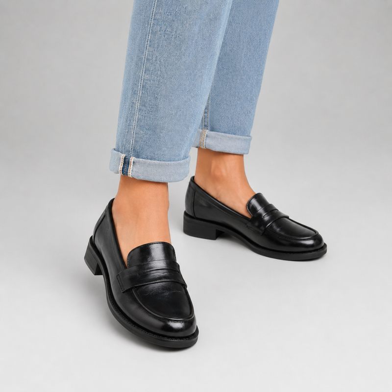 Mocassin à talon en cuir vernis noir pour femme porté avec un jean clair